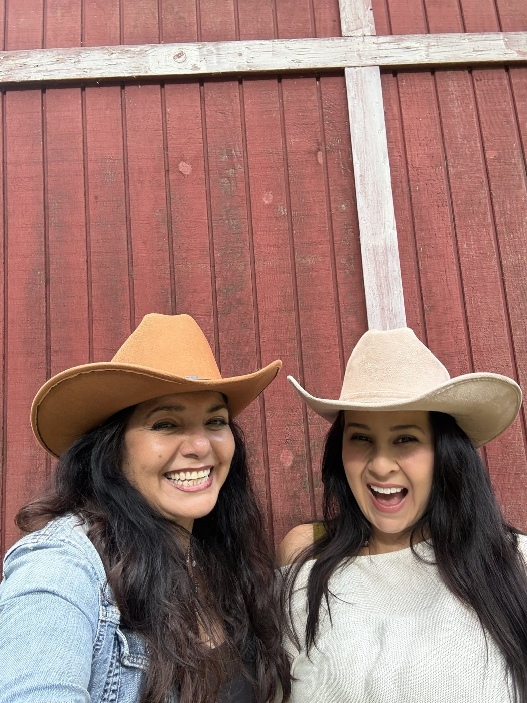 Angie y Melissa con sombreros vaqueros frente a un granero rojo